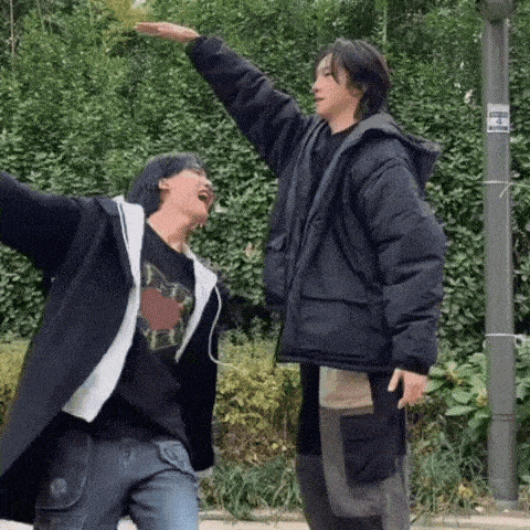 two young men are standing next to each other with their arms outstretched and one of them is taller than the other .