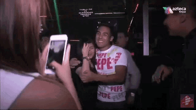 a woman taking a picture of a man wearing a pepe shirt