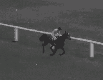 a black and white photo of a jockey riding a horse .