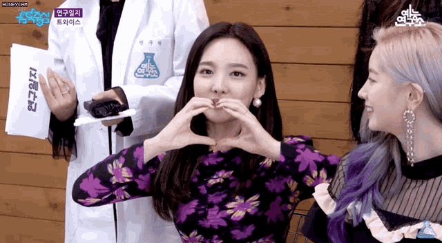 a woman in a purple dress making a heart shape