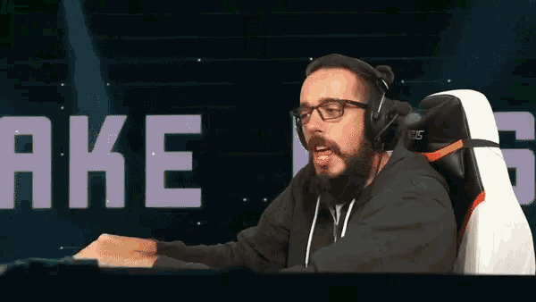 a man wearing headphones is sitting in front of a screen that says " ake "