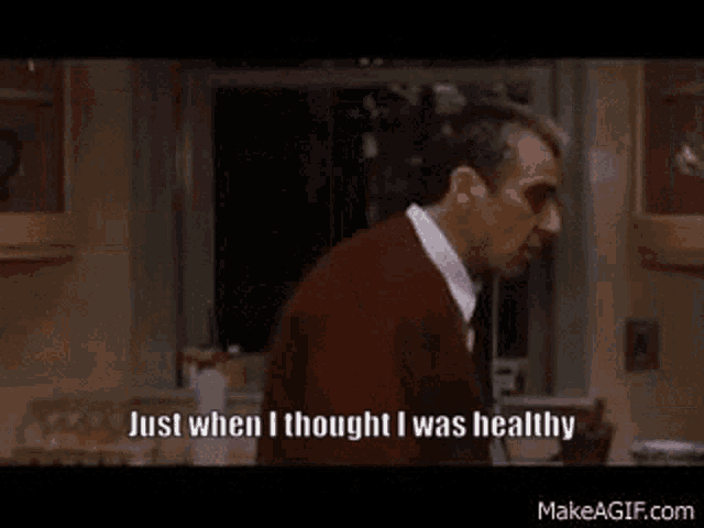 a man in a red sweater is standing in a kitchen and says `` just when i thought i was healthy ''