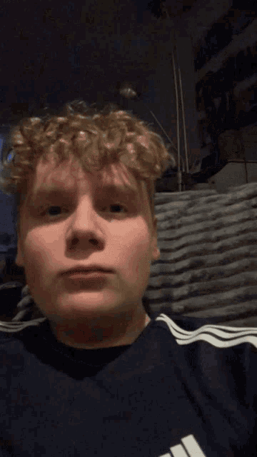 a young man wearing an adidas shirt makes a face