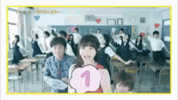 a girl is holding a fan with the number 1 on it in front of a crowd of people