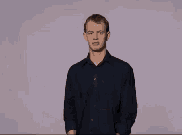 a man wearing a blue shirt is making a gesture with his hands