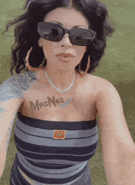 a woman wearing sunglasses has a tattoo on her chest that says mrs. nos