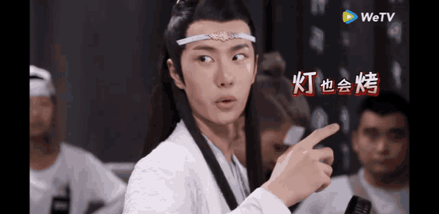 a man wearing a white shirt and a headband is pointing at something