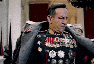 a man in a military uniform with a lot of medals on his chest is standing in a room .