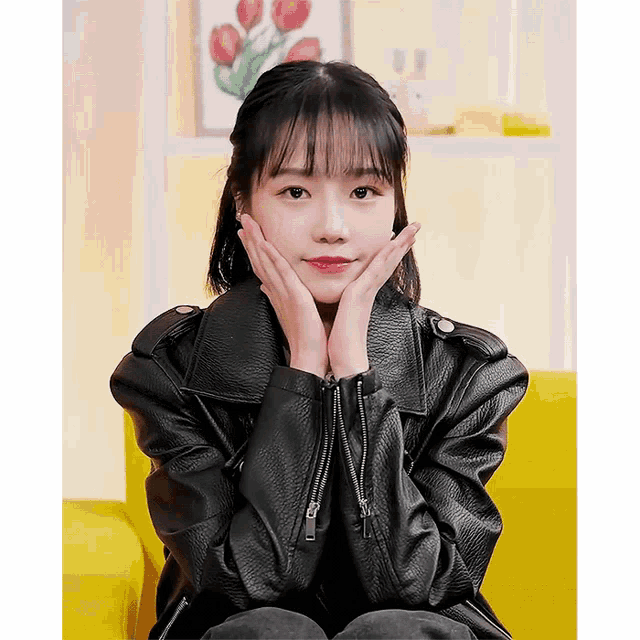 a girl in a black leather jacket sitting on a yellow couch
