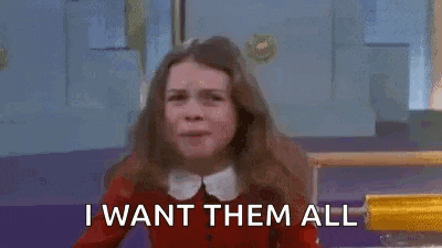 a girl in a red sweater is saying `` i want them all '' with her arms in the air .