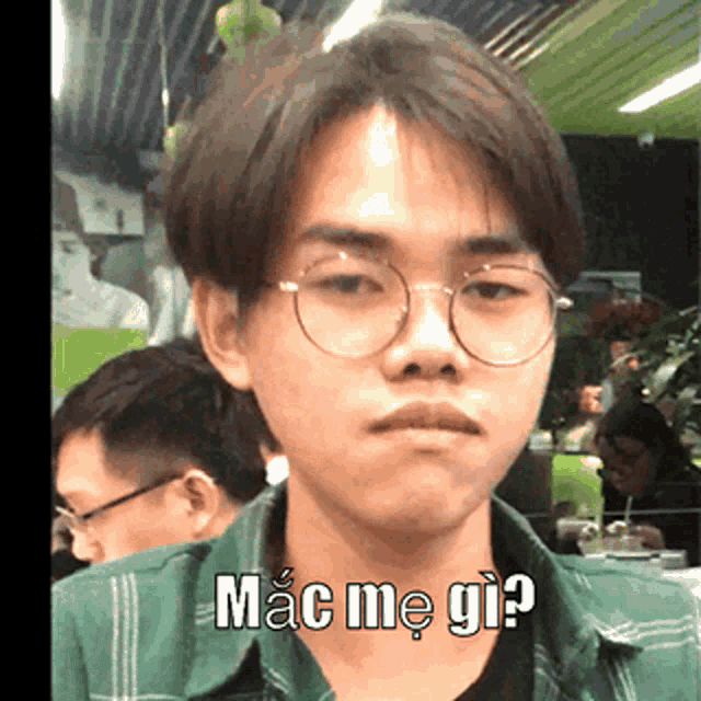 a young man wearing glasses and a green shirt says mac me gi?