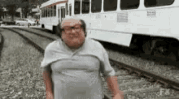 a man is standing on a train track in front of a bus .