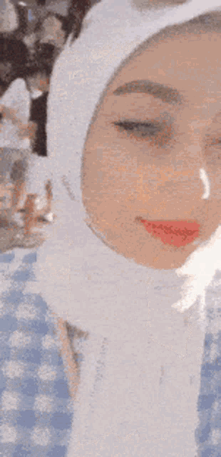 a close up of a woman wearing a white hood and red lipstick