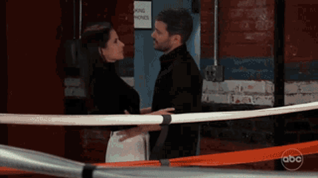 a man and a woman are hugging in a boxing ring with a sign that says parking phones