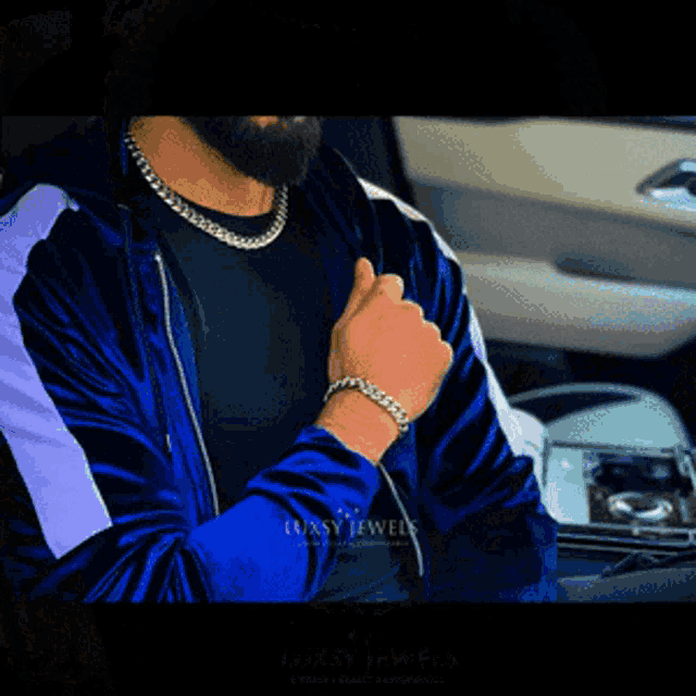 a man wearing a blue velvet jacket and a silver chain necklace