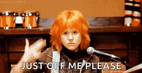 a woman with red hair is sitting in front of a microphone and says just off me please