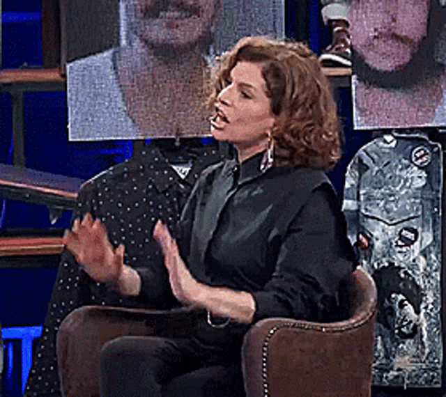 a woman in a black shirt is sitting in a chair with her hands out