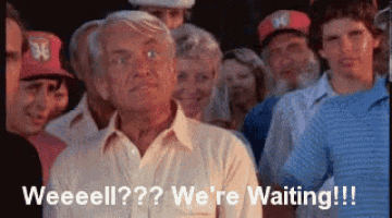 an older man is standing in a crowd of people and says weeeeell ?? we 're waiting !!!