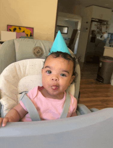 a baby in a high chair with a party hat on her head