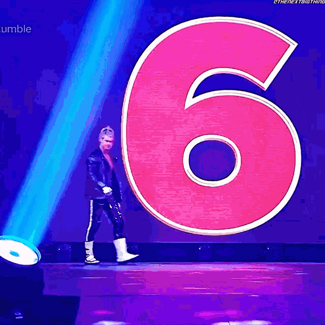 a wrestler is walking in front of a large pink number six