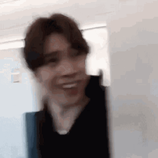 a blurry picture of a man making a funny face while standing in a room .