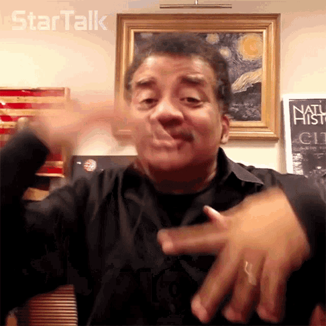 a man making a gesture in front of a sign that says startalk