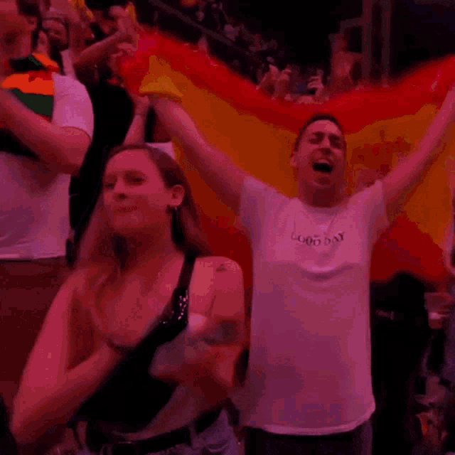 a man in a white t-shirt that says good day is holding a flag