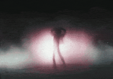 a silhouette of a person standing in a dark room with a pink light behind them