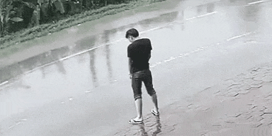 a man is standing on the sidewalk in the rain .