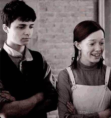 a boy and a girl are standing next to each other in front of a brick wall .
