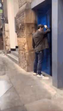 a man is knocking on a blue door with a sign that says ' a ' on it