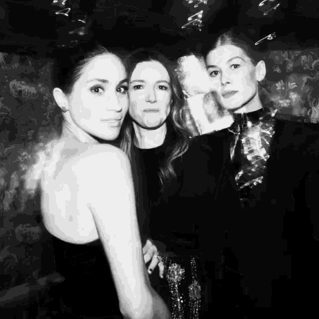 a black and white photo of three women posing for the camera