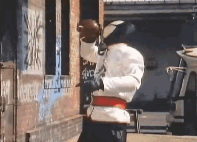 a man in a bee suit is standing in front of a building with graffiti on it that says avc
