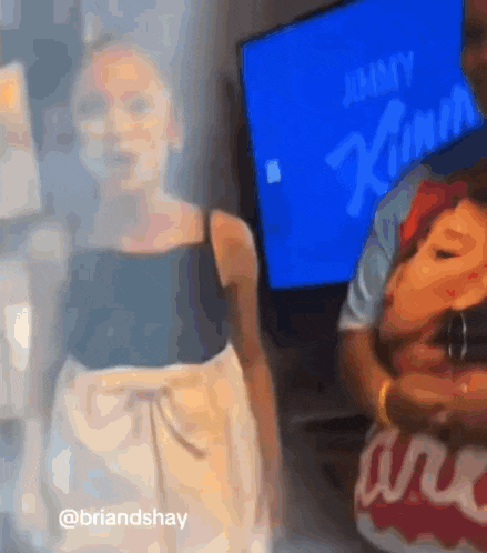 a blurry picture of a woman standing in front of a tv screen that says jimmy kimmel on it
