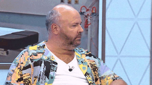 a bald man with a beard is wearing a colorful shirt and a white shirt