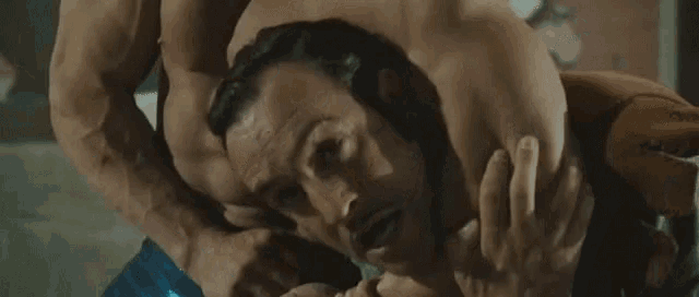 a man is laying on top of another man in a wrestling match .