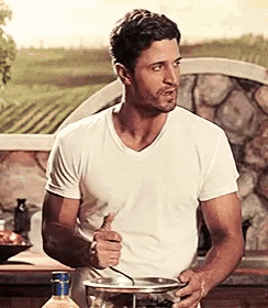 a man in a white shirt is stirring something in a bowl with a spoon