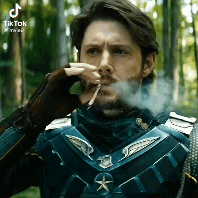 a man in a superhero costume is smoking a cigarette in the woods ..