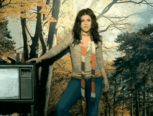 a woman in a scarf stands in front of a television that says fox on it