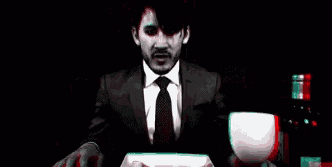 a man in a suit and tie is standing in front of a computer screen in a dark room .