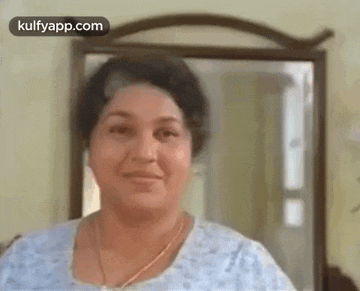 a woman is smiling in front of a mirror and looking at herself in the mirror .