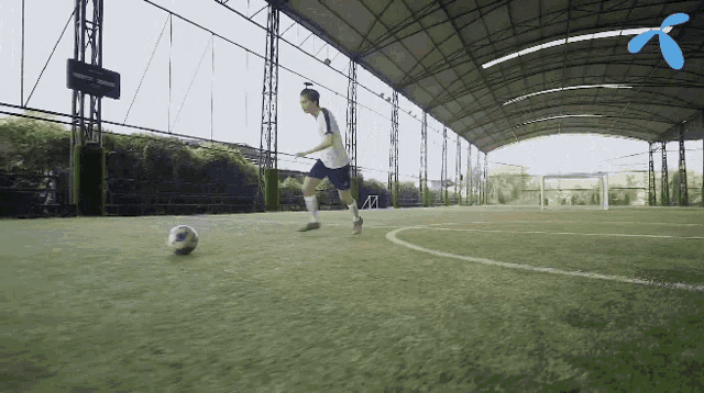 a man is kicking a soccer ball on a field with a blue t on the roof