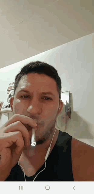 a man is smoking a cigarette and wearing ear buds