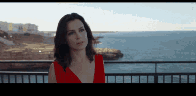 a woman in a red dress is looking out over the ocean