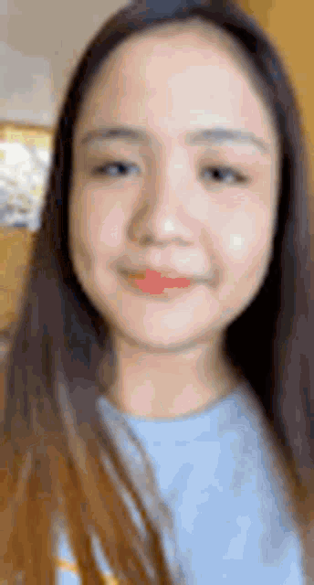a close up of a young woman 's face with long hair and a blue shirt .