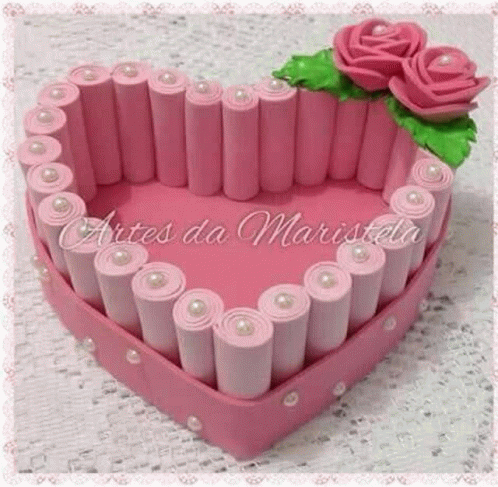 a pink heart shaped box with pink roses and pearls on it .