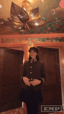 a woman in a military uniform is standing in a room with a sign that says emp