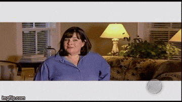 a woman in a blue shirt is sitting on a couch with a lamp in the background