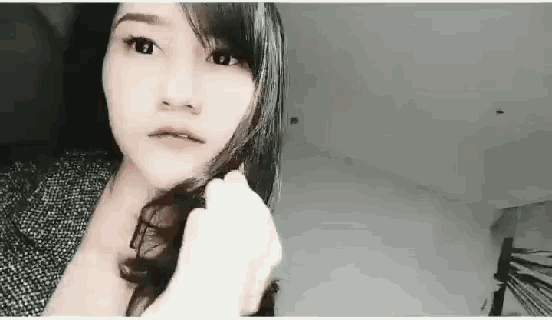 a woman is looking at the camera while holding her hair .