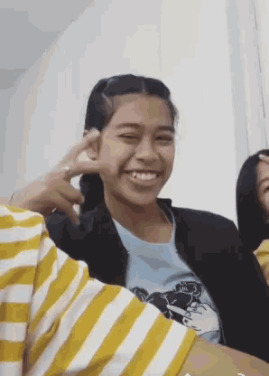 a girl wearing a yellow and white striped shirt smiles for the camera